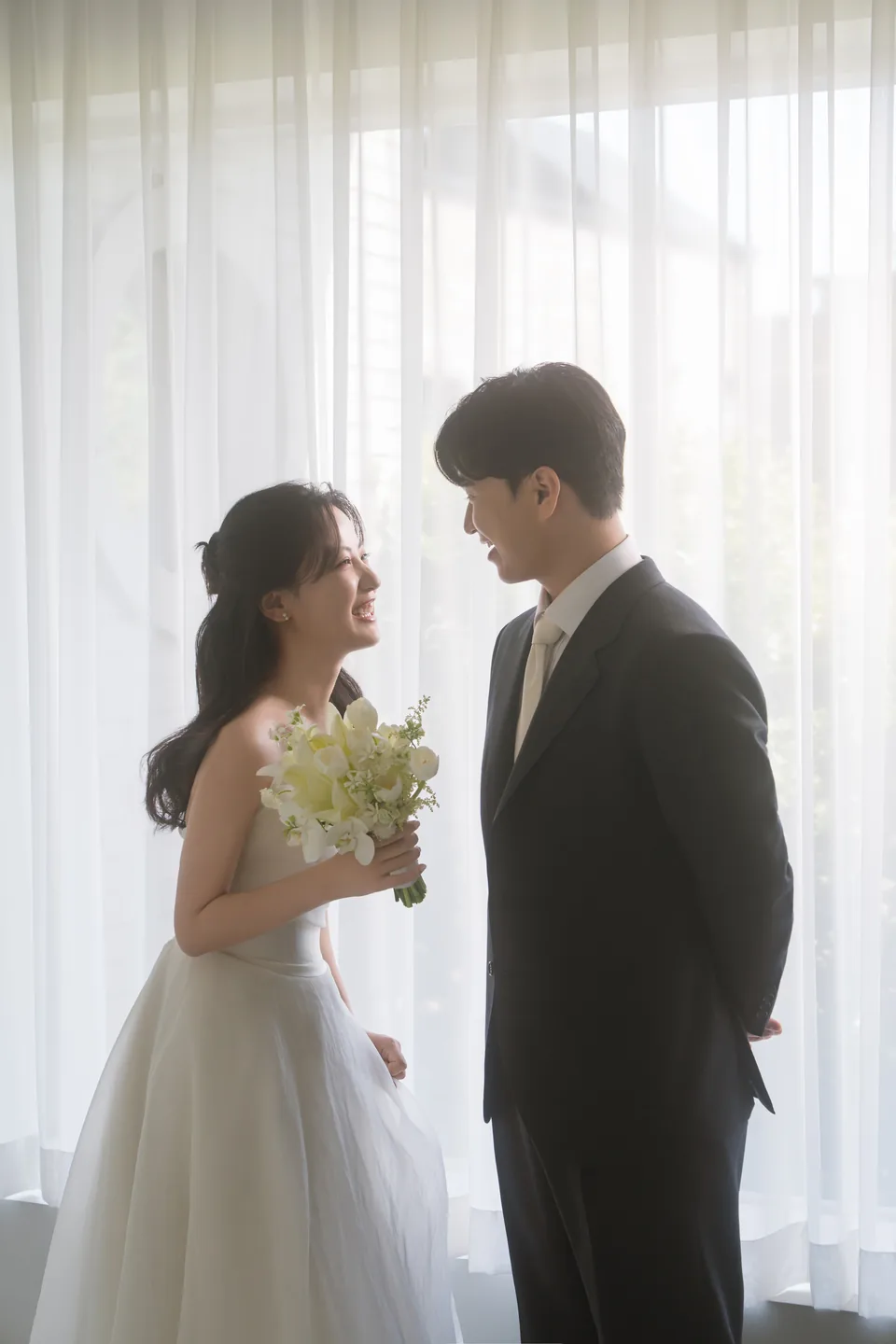 커튼 앞에서 서로 마주 보고 웃는 두 사람